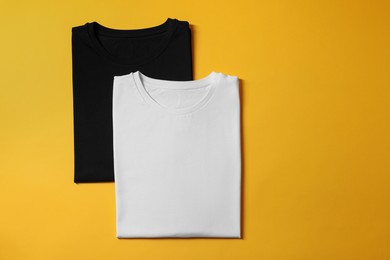 Photo of Different blank t-shirts on yellow background, top view. Mockup for design