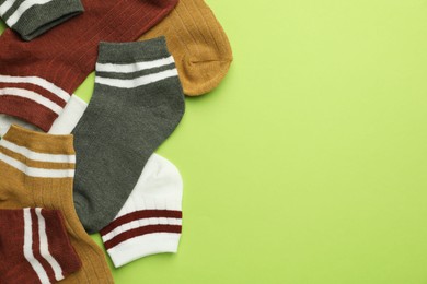 Photo of Different soft socks on light green background, flat lay. Space for text