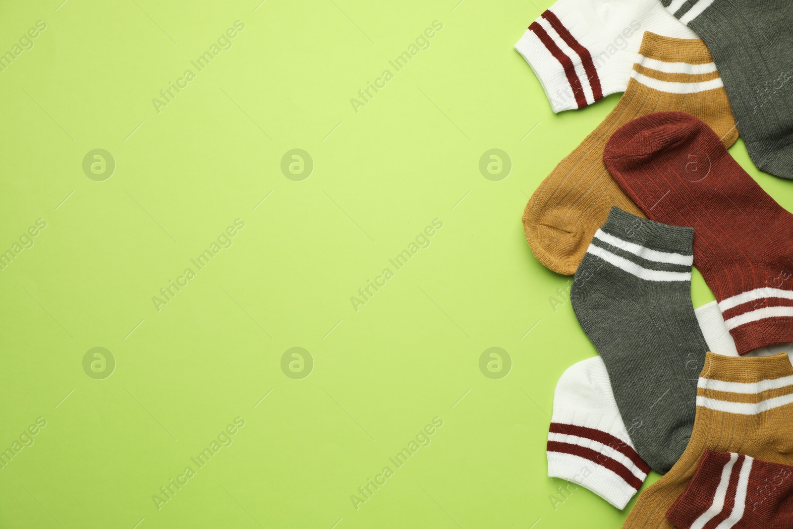 Photo of Different soft socks on light green background, flat lay. Space for text