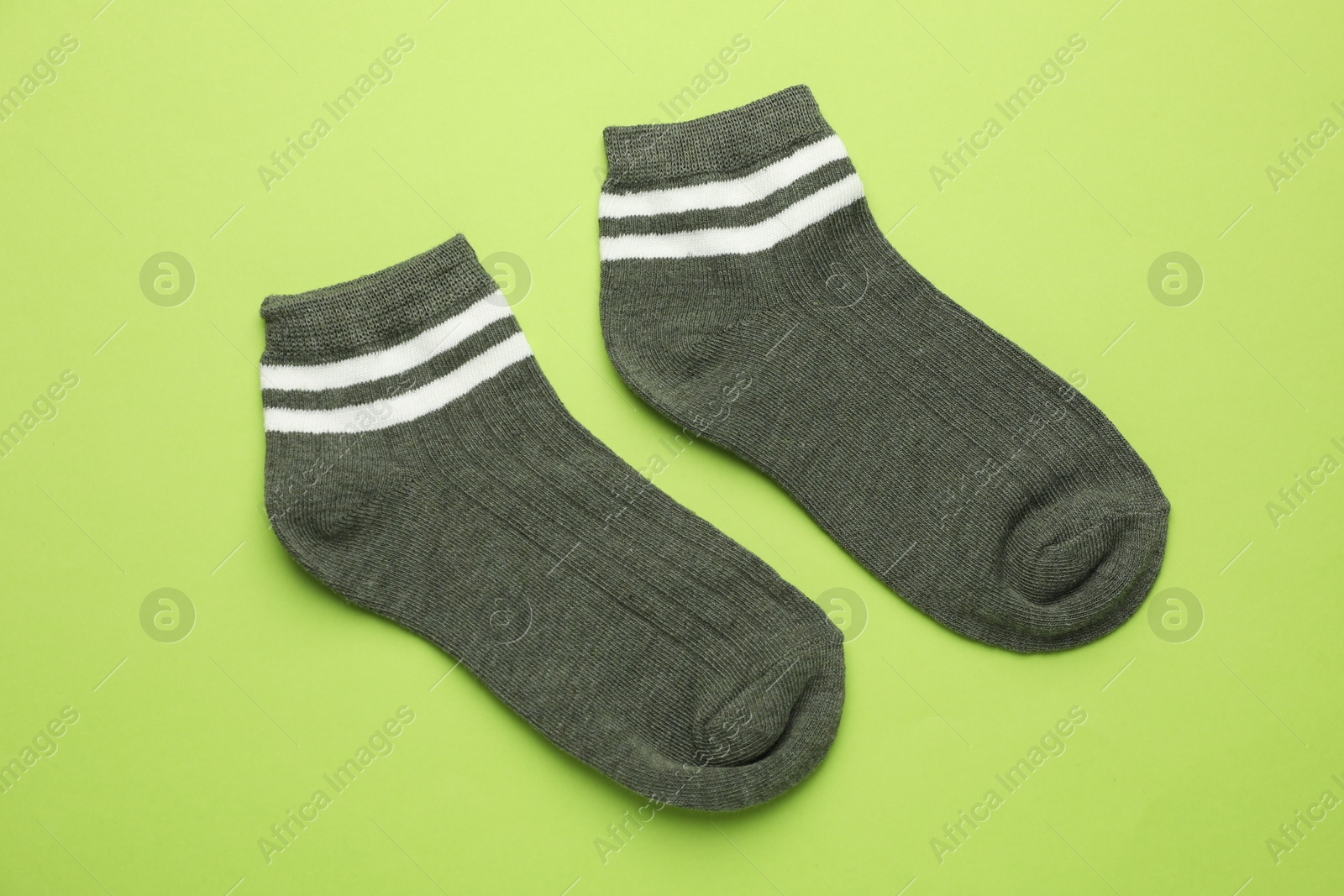 Photo of Pair of soft socks on light green background, top view