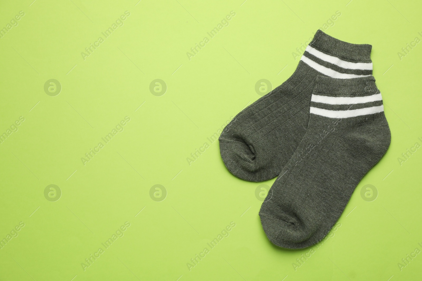 Photo of Pair of soft socks on light green background, top view. Space for text