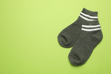 Photo of Pair of soft socks on light green background, top view. Space for text