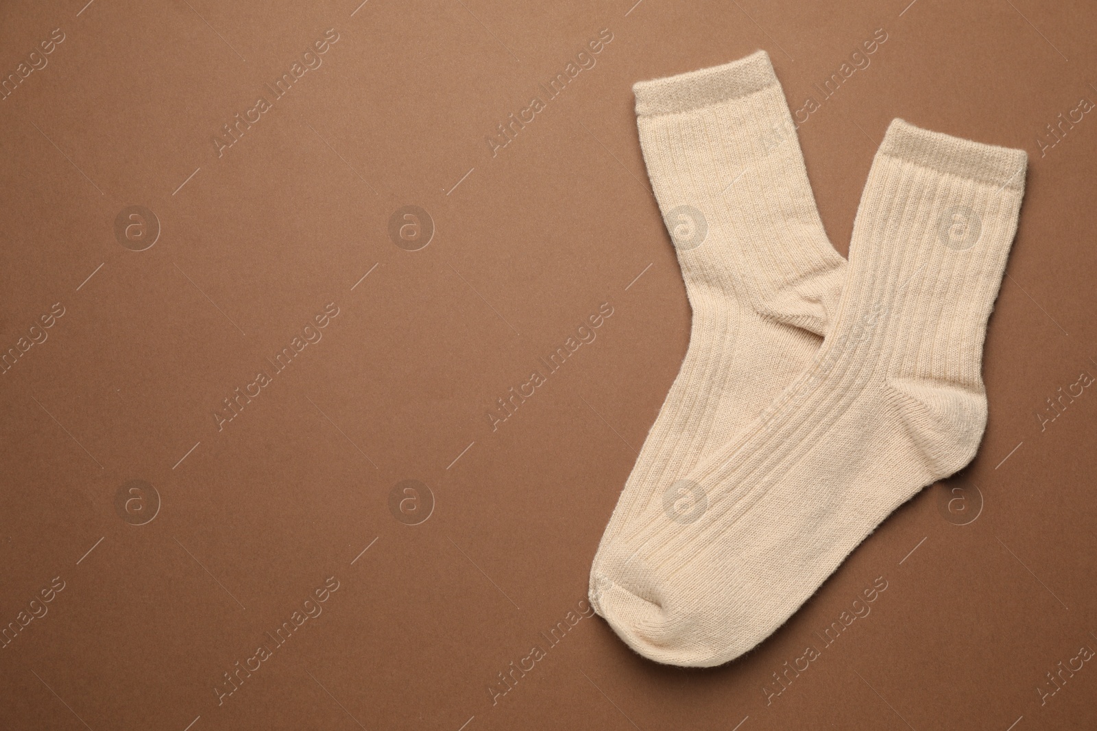 Photo of Pair of soft socks on light brown background, top view. Space for text