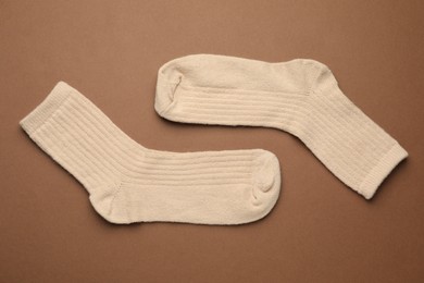 Photo of Pair of soft socks on light brown background, top view