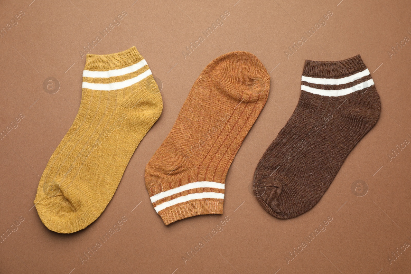 Photo of Different soft socks on light brown background, flat lay