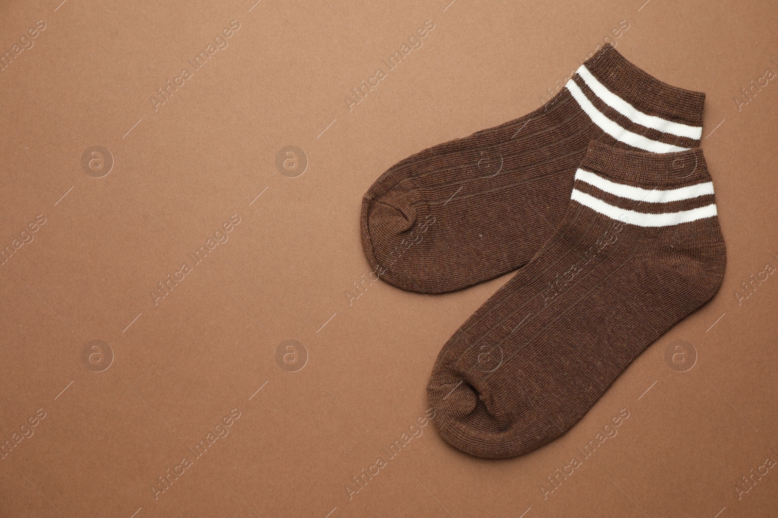 Photo of Pair of soft socks on light brown background, top view. Space for text