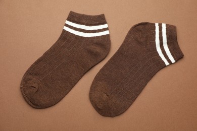 Photo of Pair of soft socks on light brown background, top view