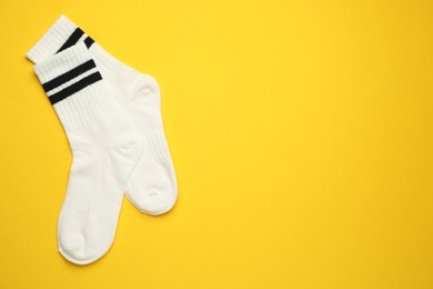 Photo of Pair of soft socks on yellow background, top view. Space for text