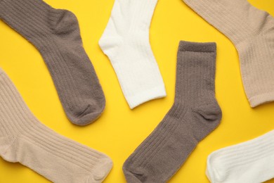 Photo of Different soft socks on yellow background, flat lay