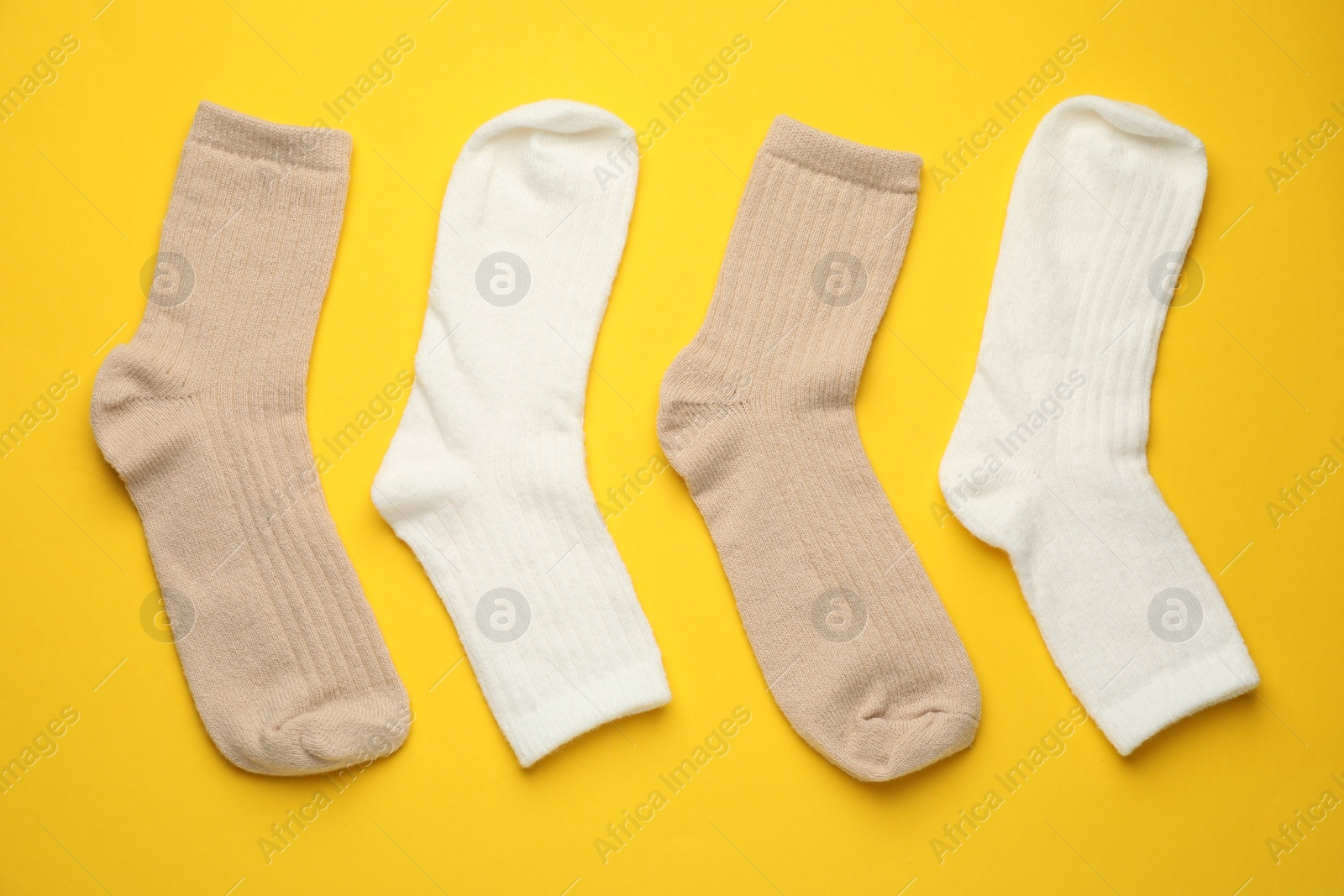 Photo of Different soft socks on yellow background, flat lay