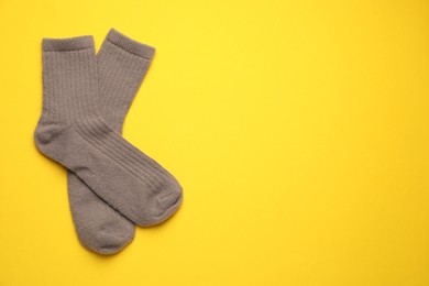 Photo of Pair of soft socks on yellow background, top view. Space for text