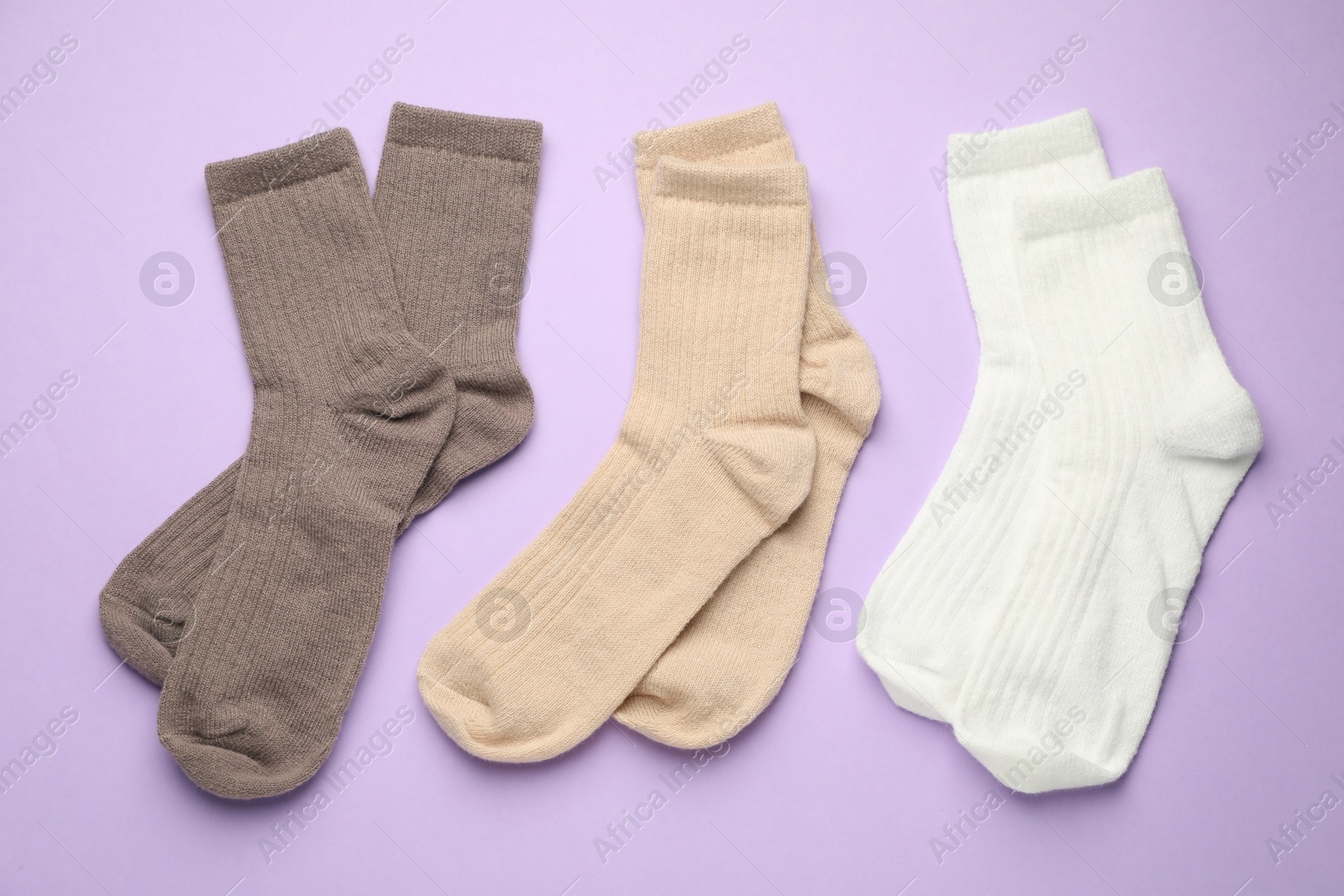 Photo of Different soft socks on violet background, flat lay