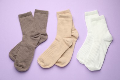 Photo of Different soft socks on violet background, flat lay