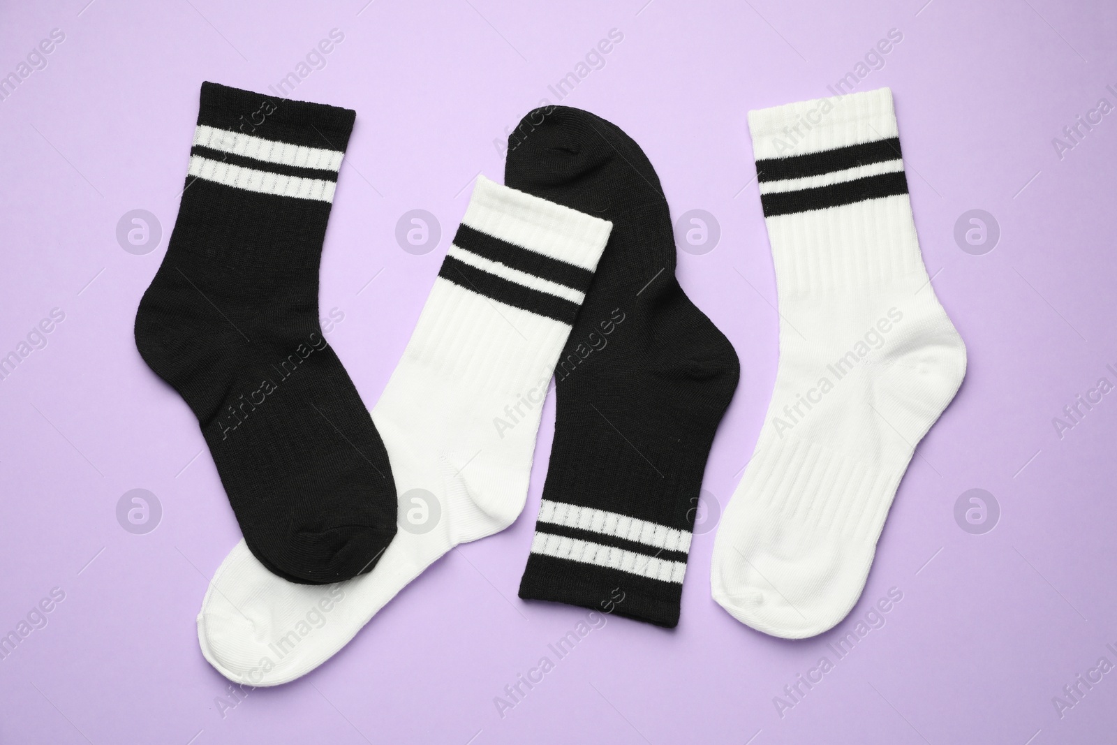 Photo of Different soft socks on violet background, flat lay