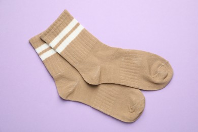 Photo of Pair of soft socks on violet background, top view