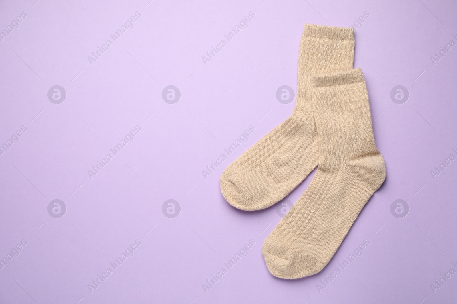 Photo of Pair of soft socks on violet background, top view. Space for text