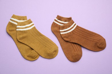 Photo of Different soft socks on violet background, flat lay