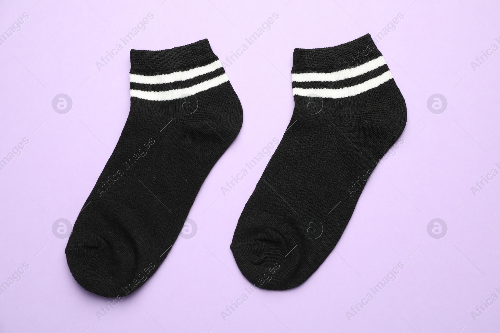 Photo of Pair of soft socks on violet background, top view