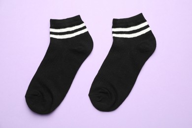 Photo of Pair of soft socks on violet background, top view