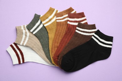 Photo of Different soft socks on violet background, flat lay