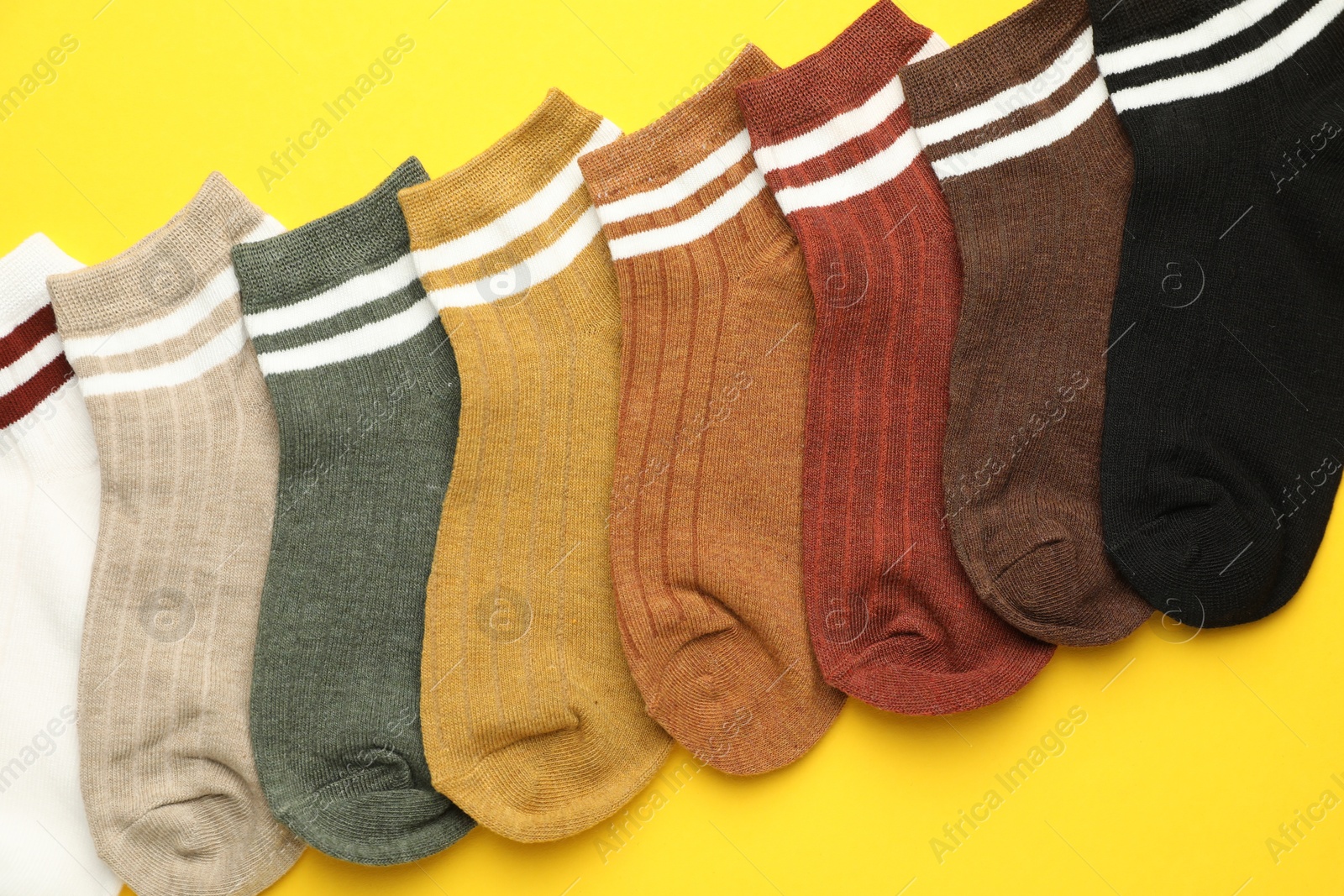 Photo of Different soft socks on yellow background, flat lay