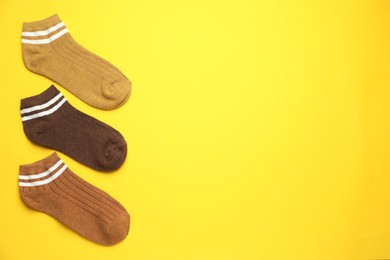 Photo of Different soft socks on yellow background, flat lay. Space for text