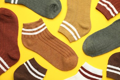 Photo of Different soft socks on yellow background, flat lay