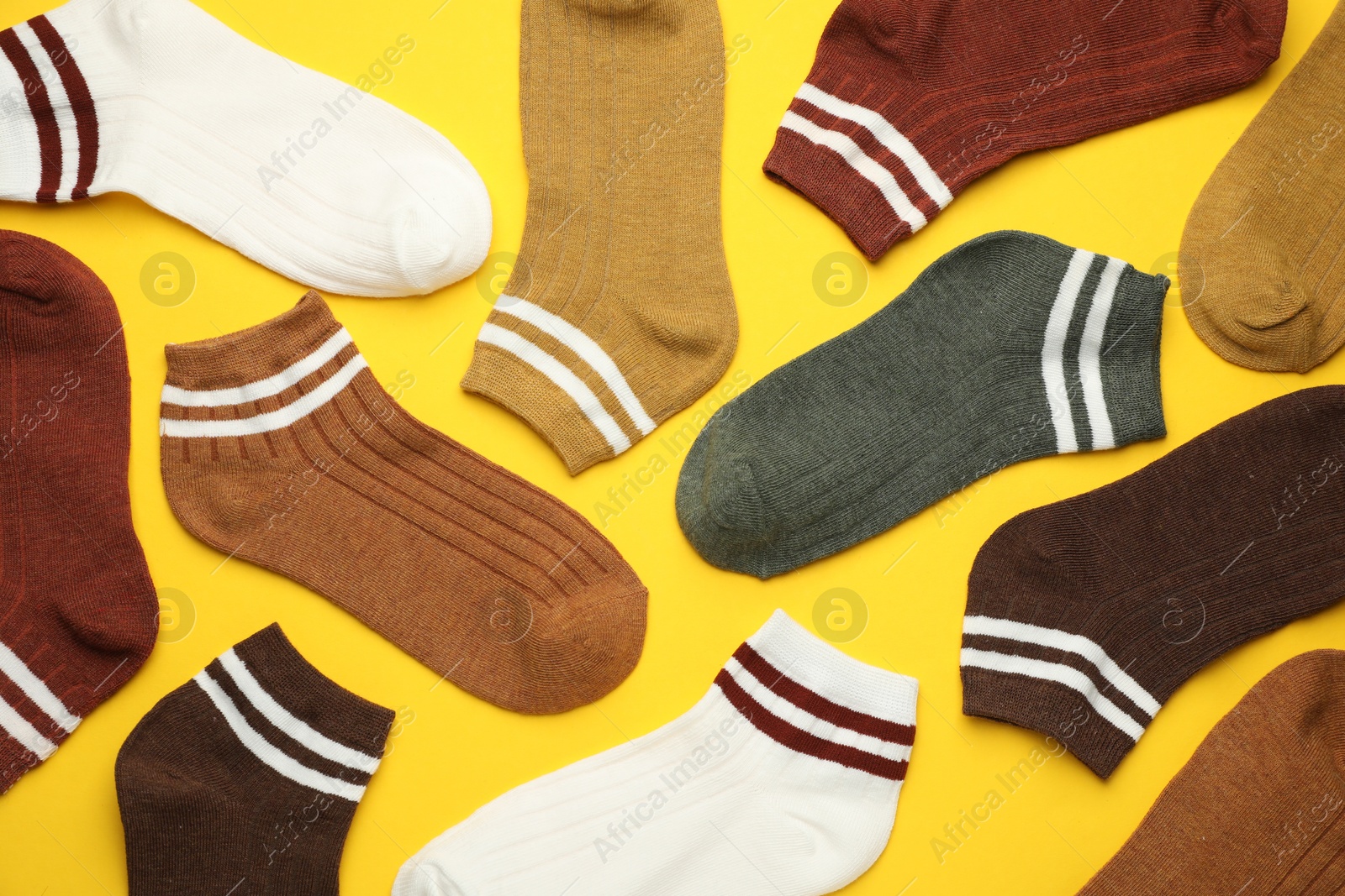 Photo of Different soft socks on yellow background, flat lay