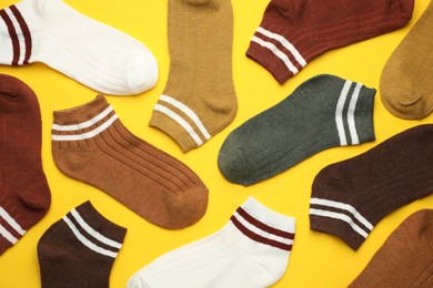 Photo of Different soft socks on yellow background, flat lay