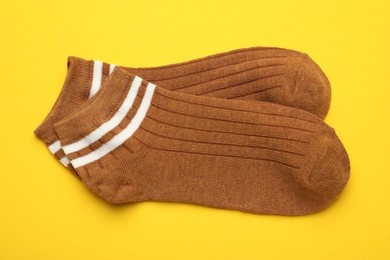 Photo of Pair of soft socks on yellow background, top view