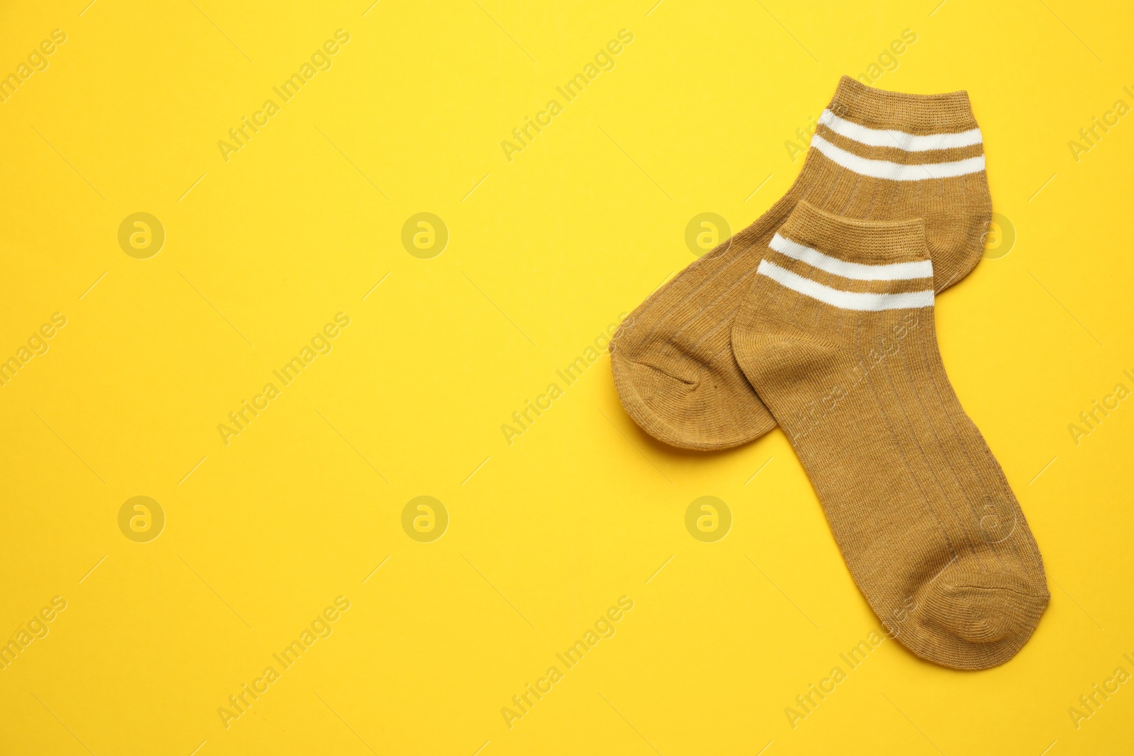 Photo of Pair of soft socks on yellow background, top view. Space for text