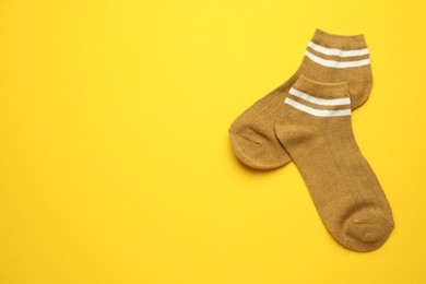 Photo of Pair of soft socks on yellow background, top view. Space for text