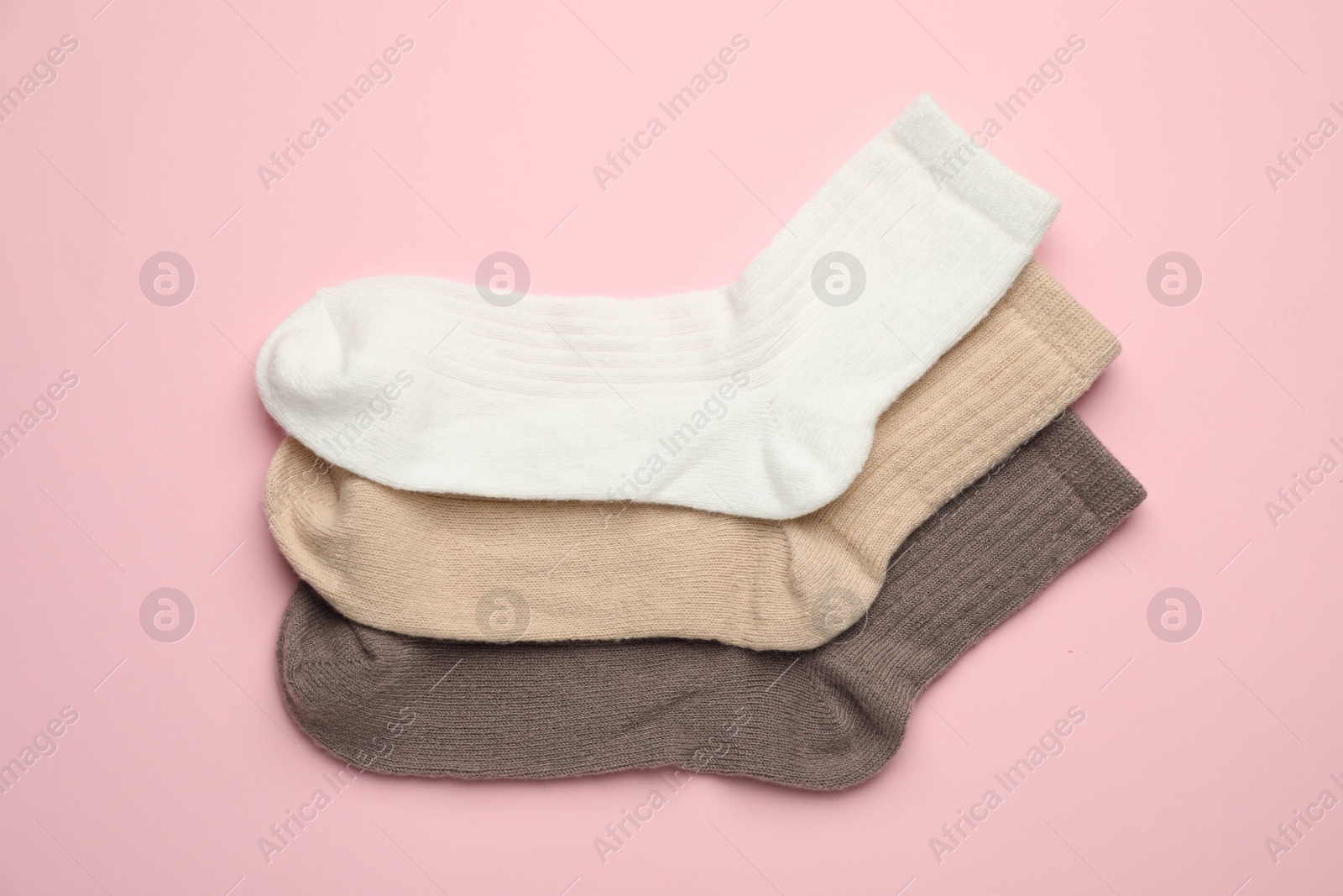 Photo of Different soft socks on pink background, flat lay