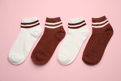 Photo of Different soft socks on pink background, flat lay