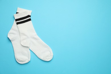 Photo of Pair of soft socks on light blue background, top view. Space for text