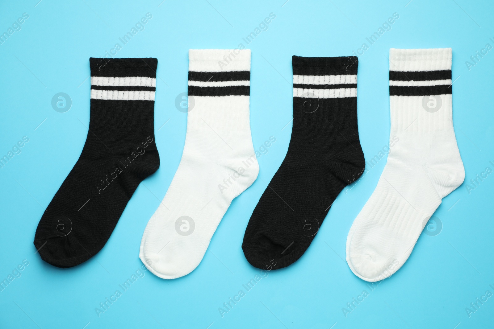 Photo of Different soft socks on light blue background, flat lay