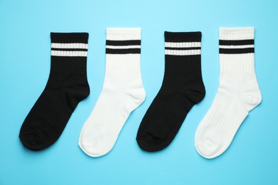 Photo of Different soft socks on light blue background, flat lay