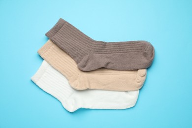 Photo of Different soft socks on light blue background, flat lay