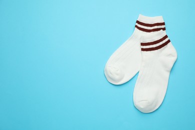 Photo of Pair of soft socks on light blue background, top view. Space for text