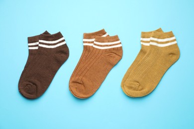 Photo of Different soft socks on light blue background, flat lay