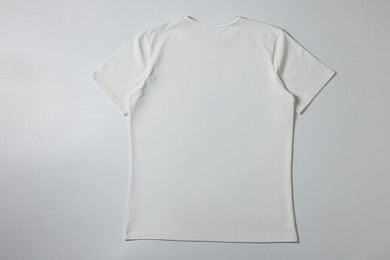 Photo of One blank t-shirt on white background, top view. Mockup for design