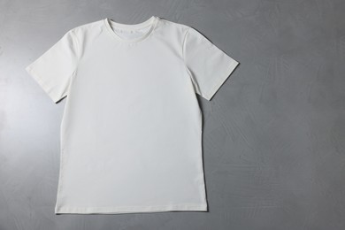 Photo of One blank t-shirt on grey textured background, top view. Mockup for design