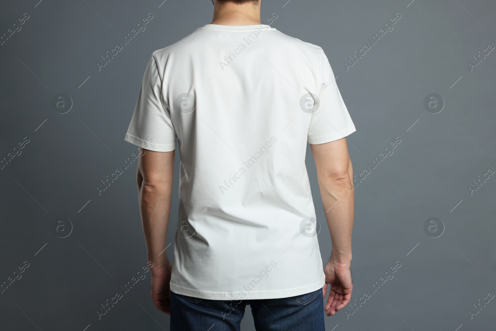 Photo of Man in blank white t-shirt on grey background, back view. Mockup for design