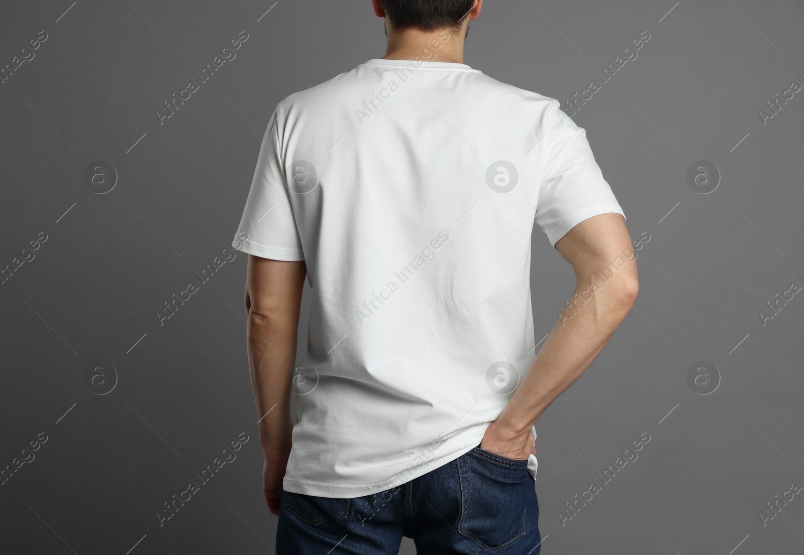 Photo of Man in blank white t-shirt on grey background, back view. Mockup for design