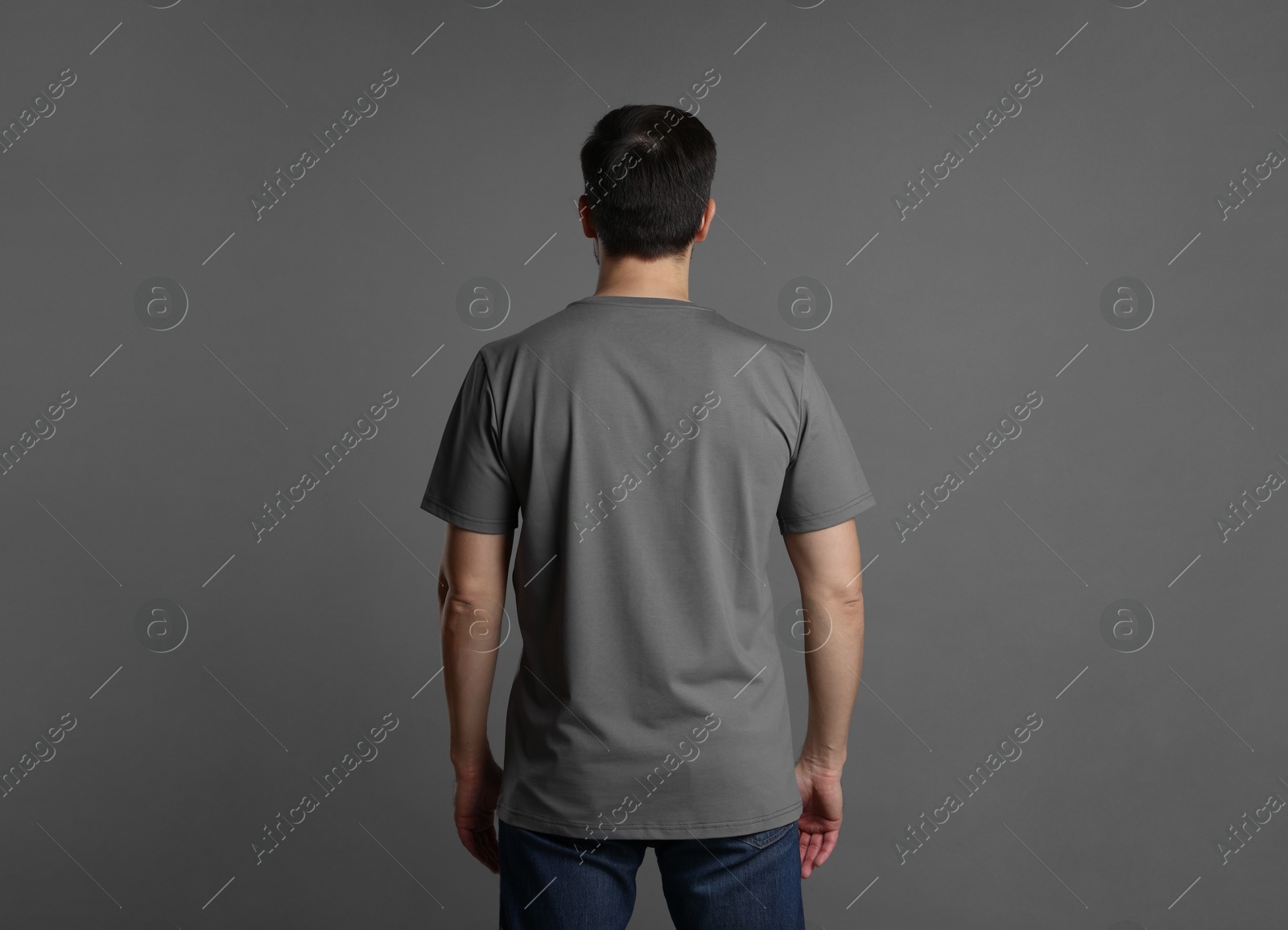 Photo of Man in blank t-shirt on grey background, back view. Mockup for design