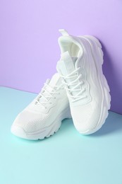 Photo of Pair of stylish white sneakers on color background