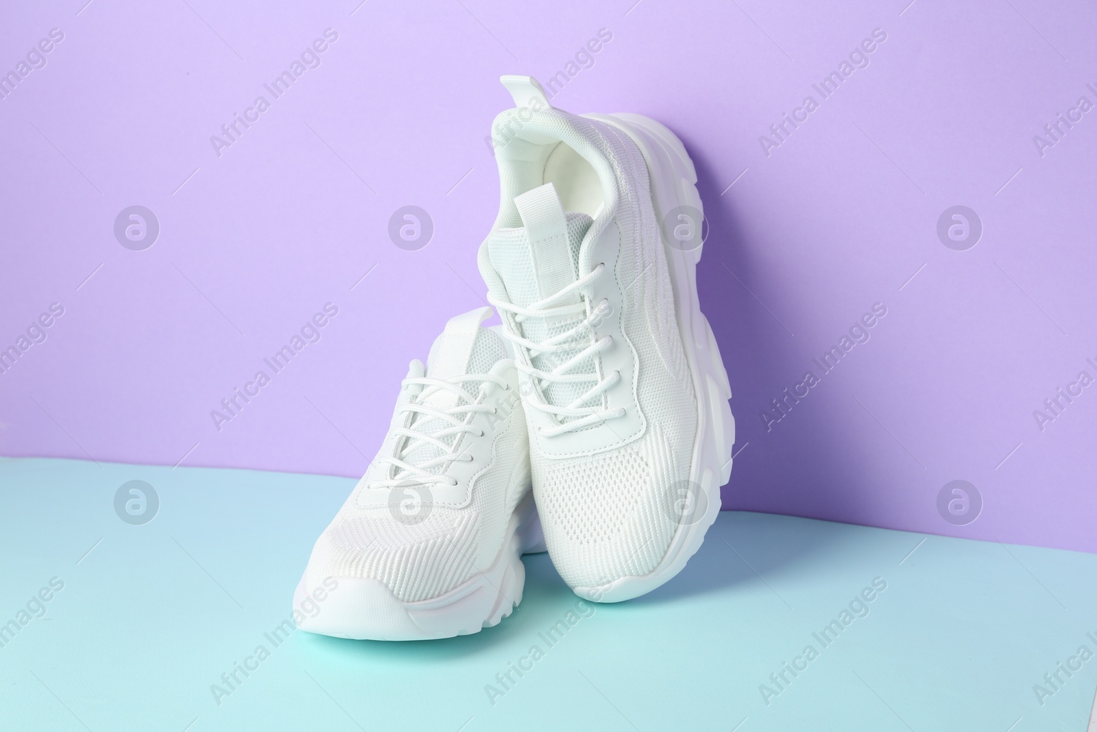 Photo of Pair of stylish white sneakers on color background