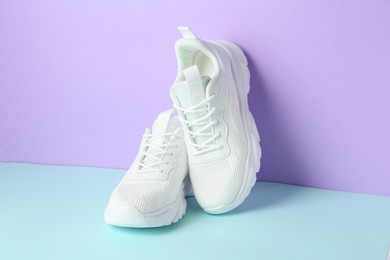 Photo of Pair of stylish white sneakers on color background