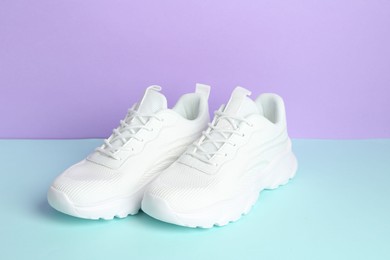 Photo of Pair of stylish white sneakers on color background