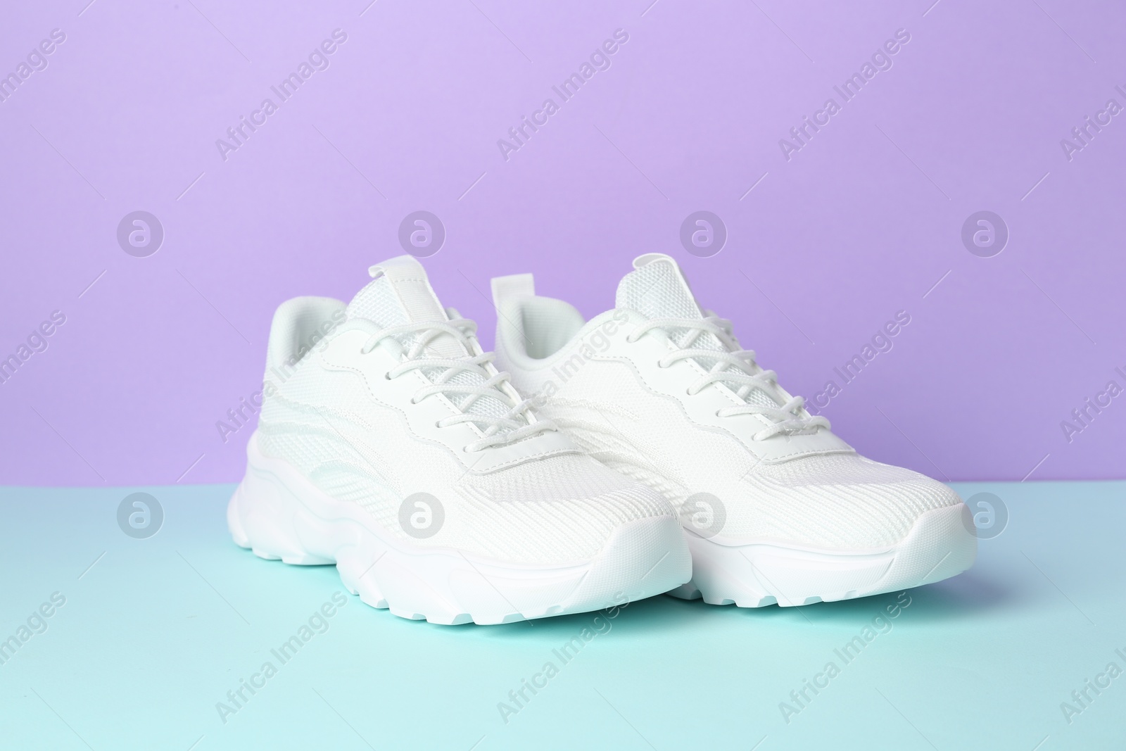 Photo of Pair of stylish white sneakers on color background